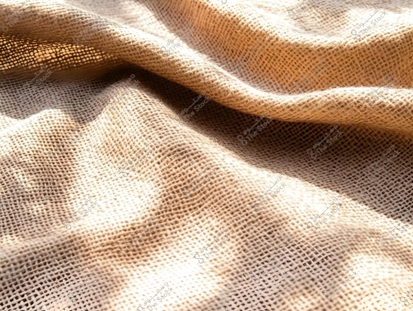 Image of a beige fabric, likely burlap, with a rough texture and mesh-like pattern. The lighting casts contrasts and shadows highlighting the waves in the fabric.