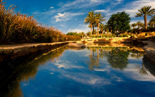 لقطة جمالية لبركة ماء في الدرعية القديمة ويظهر انعكاس السماء و النخيل فيها.