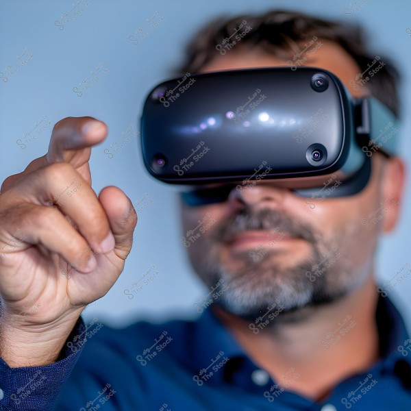 An image of a man wearing black virtual reality goggles, visible in a blurred background. The man is wearing a dark blue shirt and appears to be interacting with a virtual environment by pointing with his finger.