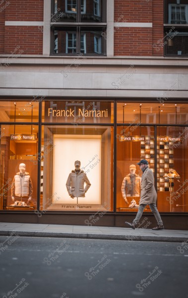 شخص يمشي أمام واجهة متجر فرانك ناماني ويعرض بعض الأزياء الشتوية.