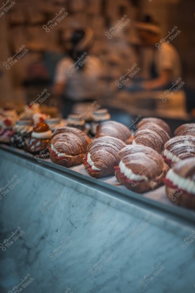 Pastries filled with cream and berries displayed in a bakery window.