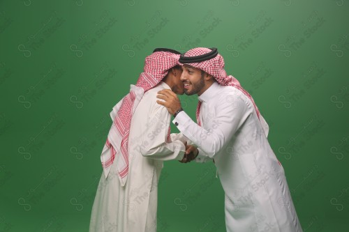 رجل سعودي يرتدي الزي السعودي التقليدي يسلم على قريبه في إحدى المناسبات، شابان سعوديان يتبادلون التحية