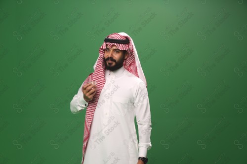 شاب سعودي على خلفية خضراء يرتدي الثوب و الشماغ، يقوم بعمل حركات بيده، يشرب القهوه السعودية، احتفالات العيد