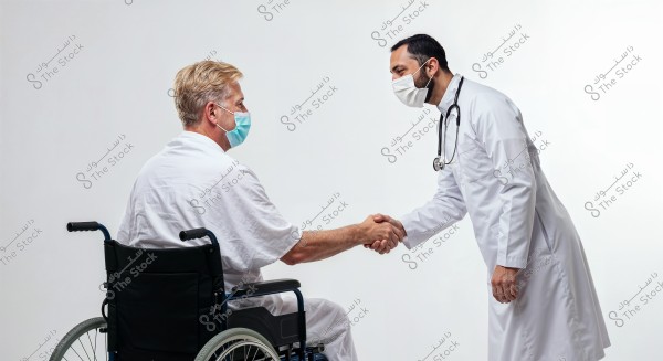 A doctor in a white coat and face mask is shaking hands with a man in a wheelchair, who is wearing a white shirt and mask. The scene depicts positive interaction in a medical setting.