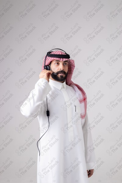 بورتريه رجل سعودي يلبس سماعة الرأس ويقوم بالتواصل عبر السماعة - خدمة العملاء ، مكالمة هاتفية