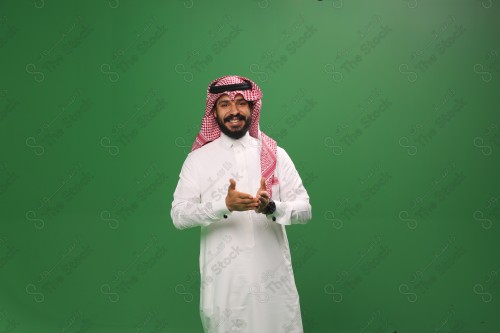 رجل سعودي يقف على خلفية خضراء يرتدي الثوب و الشماغ، يقوم بعمل حركات بيديه ، ، احتفالات العيد