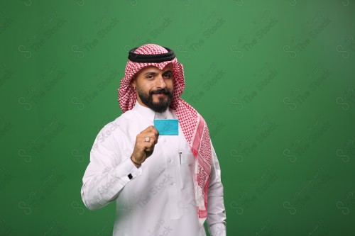 رجل سعودي على خلفية خضراء مبتسم يحمل بطاقة الصراف جاهز للتسوق