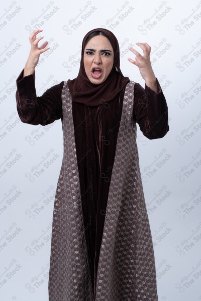 A young Saudi woman wearing an abaya and hijab, looking angry