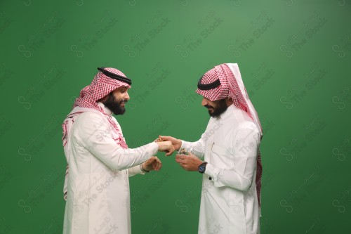 رجل سعودي يرتدي الزي السعودي التقليدي يطيب ضيفه بالدهن عود في أحد المناسبات