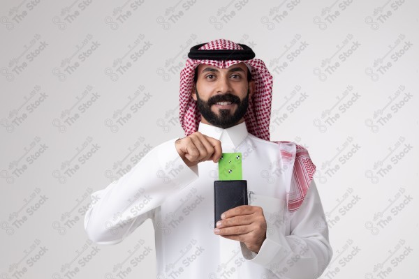 بورتريه رجل سعودي يحمل بطاقة خضراء على خلفية بيضاء