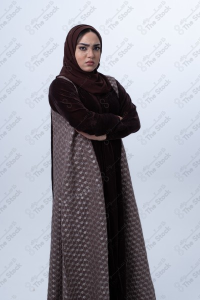 A young Saudi woman wearing an abaya and hijab, looking angry