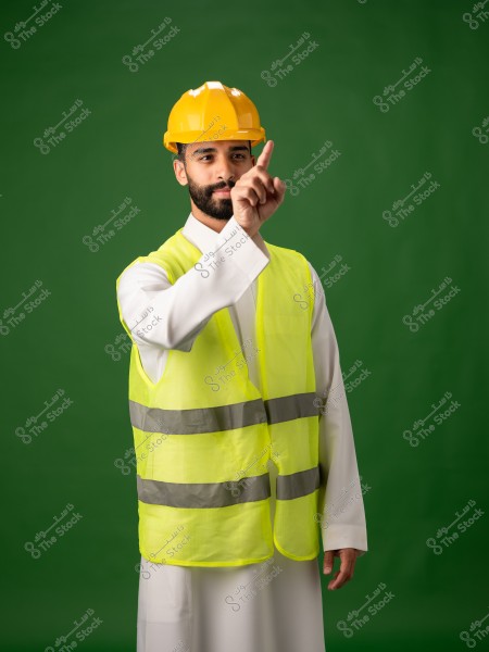 مهندس يرتدي خوذة صفراء وسترة عاكسة يقف أمام خلفية خضراء.