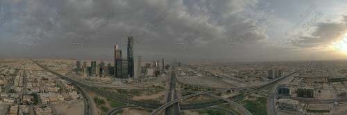 A shot showing the buildings and landmarks of the financial center of the city of Riyadh, in front of it a group of residential houses, and the sky is cloudy.