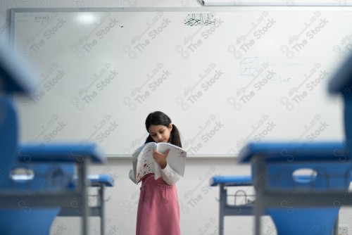 A Saudi student wears a school uniform and does different interactions and shows the tables in the classroom