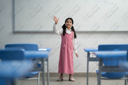 A Saudi student wears a school uniform and does different interactions and shows the tables in the classroom