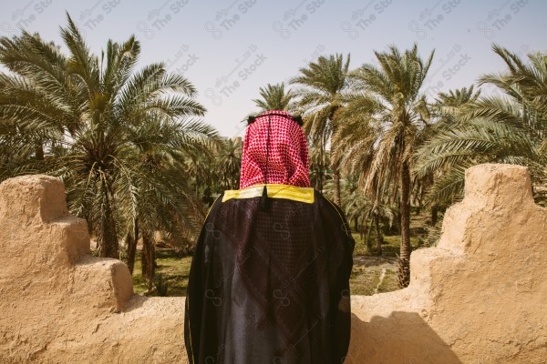 A snapshot of a Saudi man wearing folkloric costume on the day of the foundation stands over a mud building, heritage uniform, on the day of establishment, old archaeological buildings.