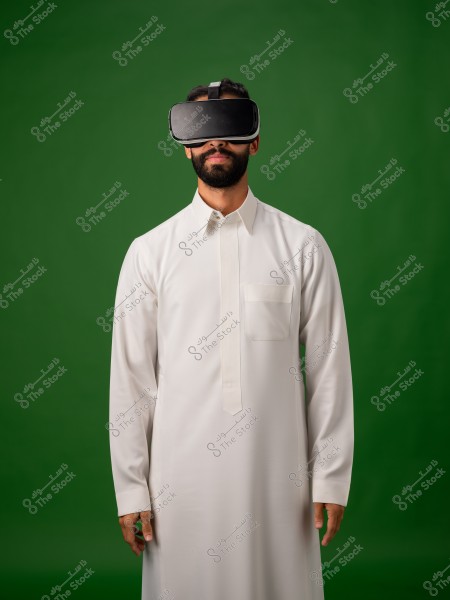 رجل يرتدي ثوبًا ونظارة واقع افتراضي أمام خلفية خضراء.