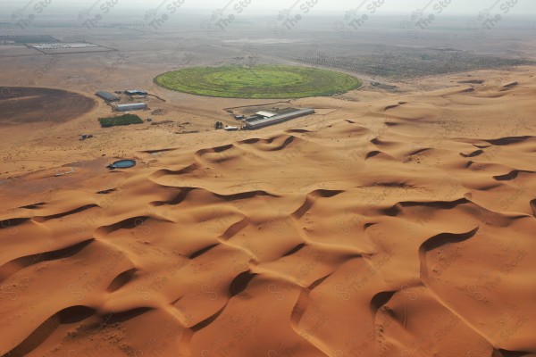 لقطة جمالية للكثبان الرملية الصحراوية بالسعودية وتظهر مزرعة في وسط الصحراء ، الرمال الذهبية في صحراء السعودية ، مناطق صحراوية .