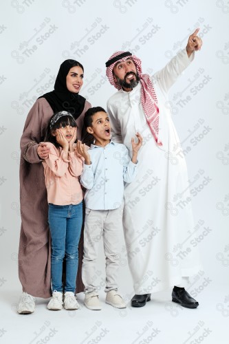 Portrait of a Saudi family looking towards a place, two children standing next to their parents pointing towards a goal, signs of happiness, a happy family atmosphere, the concept of a happy family, spending enjoyable family times