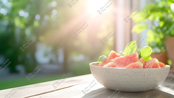 A ceramic bowl filled with slices of fresh pink fig fruit with some green mint leaves, placed on a wooden table. The background shows a lush green landscape with radiant sunlight effects.