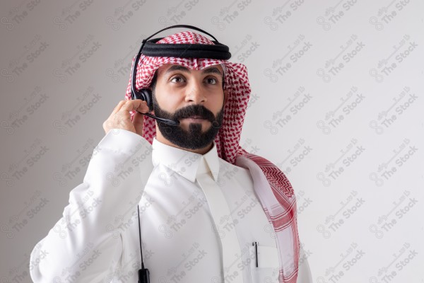 بورتريه رجل سعودي يلبس سماعة الرأس ويقوم بالتواصل عبر السماعة - خدمة العملاء ، مكالمة هاتفية