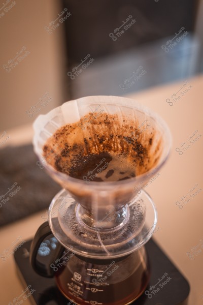 Brewing coffee using a V60 dripper with a paper filter containing wet coffee grounds.