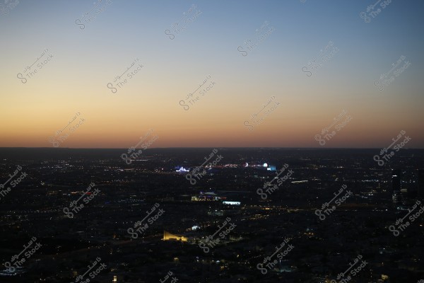 An image of a cityscape in the evening, showing a wide view of the horizon with twinkling city lights and a sky filled with sunset hues transitioning from orange to blue. Some landmarks are beautifully lit in the distance.