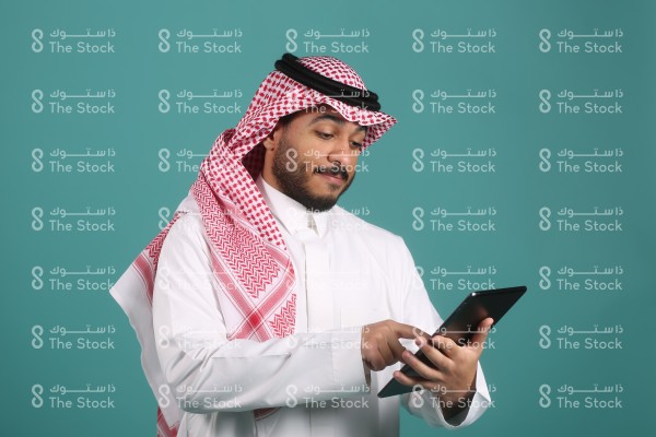 تفاعل شاب سعودي ويرتدي الزي السعودي مع الجهاز اللوحي