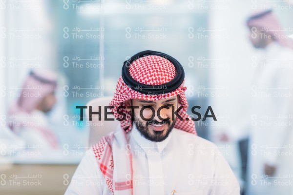 موظف سعودي مبتسم في مقر العمل.