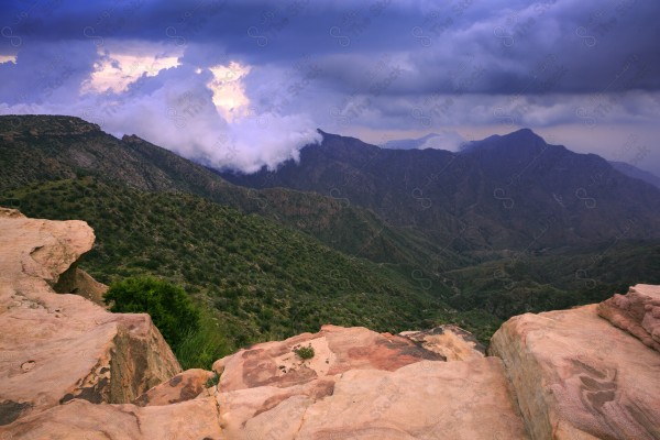 Aerial shot of a series of rocky mountains at sunset and the clouds overlapping between them, nature in Saudi Arabia, sunset