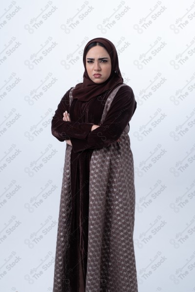 A young Saudi woman wearing an abaya and hijab, looking angry