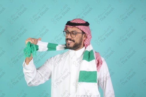 شاب سعودي يرتدي الزي السعودية ممسك شال بيده يقوم بتعابير وجه و يدين تدل على السعادة والحماس ، كأس العالم ، المنتخب السعودي.