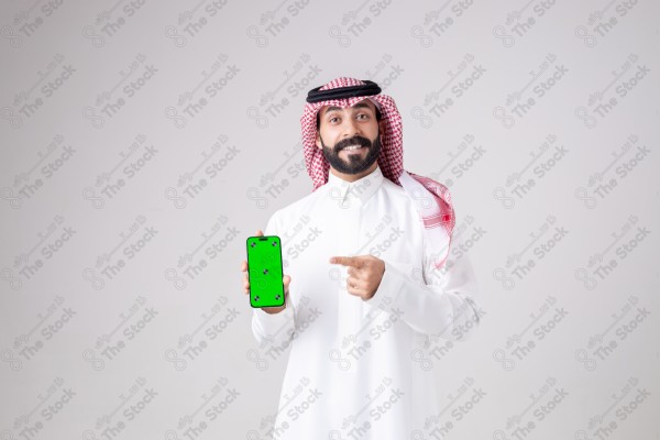 Portrait of a Saudi man holding a phone, pointing at the phone and making different expressions - green screen