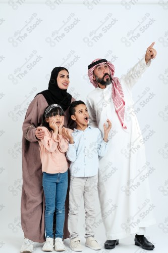 Portrait of a Saudi family looking towards a place, two children standing next to their parents pointing towards a goal, signs of happiness, a happy family atmosphere, the concept of a happy family, spending enjoyable family times