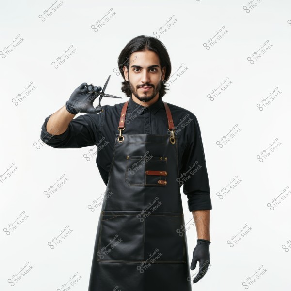 ** Image of a man wearing a black shirt and black gloves, holding a pair of scissors. He is also wearing a black leather apron with brown straps and gold metal details. The background is completely white, highlighting the details of the clothing and the scissors in his hand.\r\n\r\n**
