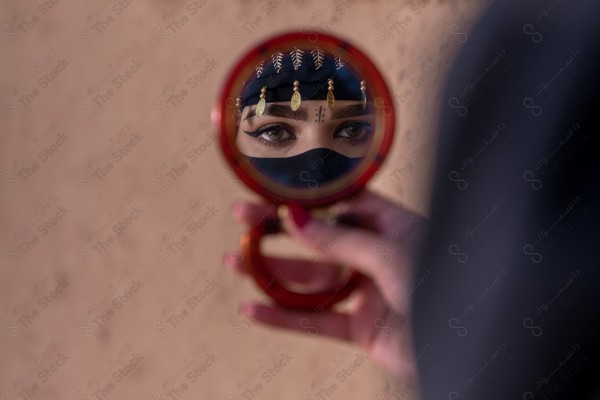 A shot of a Saudi woman whose eyes are reflected from the mirror wearing the traditional Saudi dress that represents the folklore, the day of foundation, the Saudi culture.