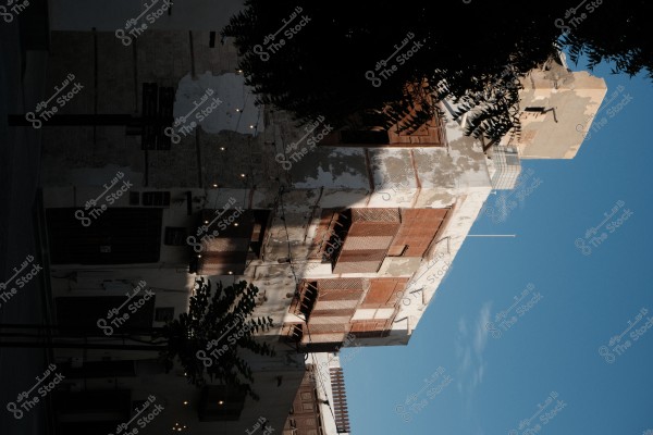 صورة لمبنى قديم بواجهات خشبية تقليدية في حي تاريخي، مع إضاءة خافتة وأوراق شجر في مقدمة الصورة.