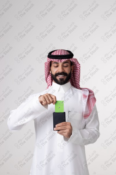 بورتريه رجل سعودي يحمل بطاقة خضراء على خلفية بيضاء