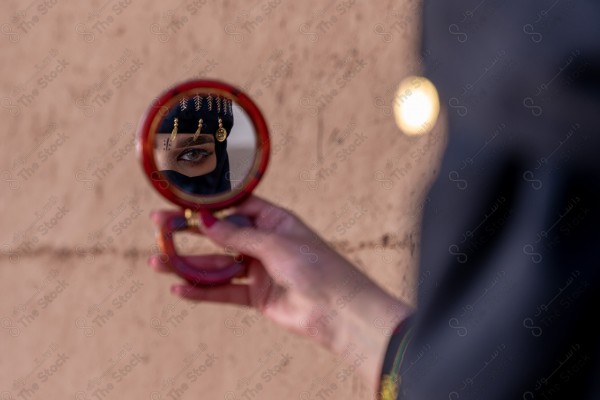 A shot of a Saudi woman whose eyes are reflected from the mirror wearing the traditional Saudi dress that represents the folklore, the day of foundation, the Saudi culture.