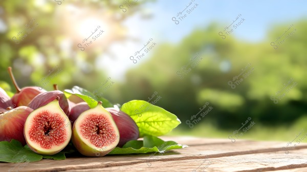 Image showing a group of figs placed on a wooden surface, with one fig cut in half prominently in the foreground, displaying its red interior and seeds. The figs are surrounded by green leaves, with a blurred natural background of green trees and bright sunlight.