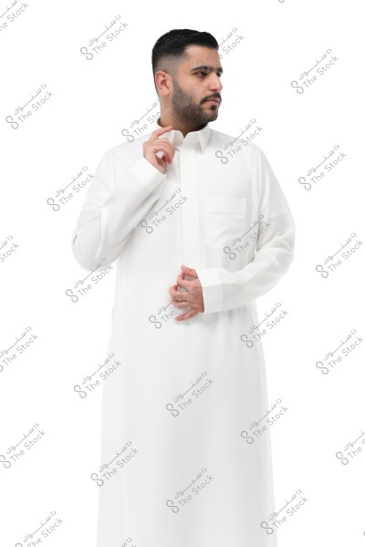 A portrait of a man wearing a traditional white thobe, shown in a side pose against a white background. The thobe features a collar, long sleeves, and a pocket on the left side. The clothing style suggests it is Saudi or Gulf.