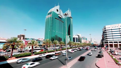 Clips showing an urban scene in Riyadh, featuring modern buildings and busy streets filled with cars under the bright sunlight.