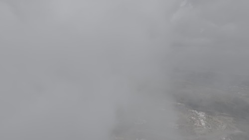 The video shows aerial footage of a mountainous area enveloped in thick fog, with buildings and roads faintly visible beneath the widespread clouds, creating a sense of tranquility amidst the foggy and vast nature.\r\n\r\n-