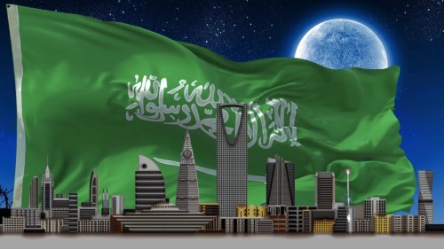 Video scene showing the Saudi Arabian flag waving in the sky with the Kingdom Tower and landmarks of Riyadh city under the moonlight.