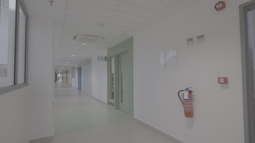 A video depicting an indoor environment of a modern, quiet building featuring clean, organized hallways with stairs, glass doors, wide corridors, and water dispensers, with people passing intermittently.