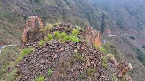 يظهر الفيديو مناظر طبيعية خلابة لجبل مع طريق متعرج يمر من خلاله. تتنوع التضاريس بين الصخور والتلال المغطاة بالنباتات الخضراء, بينما يمتد الطريق في مشهد مذهل يعكس جمال الطبيعة وهدوء المكان. \r\n\r\nبجازان