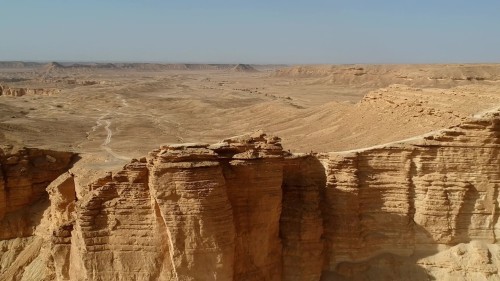 فيديو يعرض مشهداً جوياً لحافة العالم، وهي وجهة سياحية شهيرة بالقرب من الرياض, تُظهِر تشكيلات صخرية مذهلة وتضاريس رملية ممتدة على مد البصر تحت سماء زرقاء صافية.