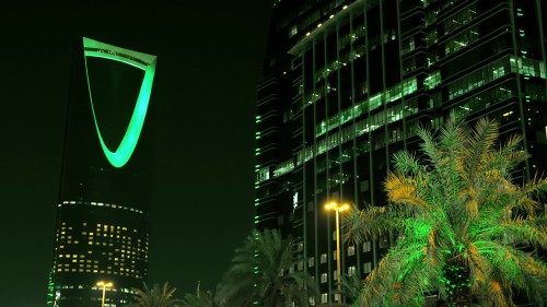 لقطات ليلية لبرج المملكة في الرياض, يضيء باللون الأخضر مع أضواء المدينة المحيطة وشجرة نخيل في المقدمة.\r\n\r\n-