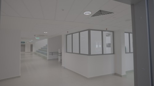 The video showcases scenes from modern hospital corridors, featuring open spaces, minimalist design, and natural lighting. It includes shots of white walls and large windows that allow natural light in, creating a sense of cleanliness and modernity.