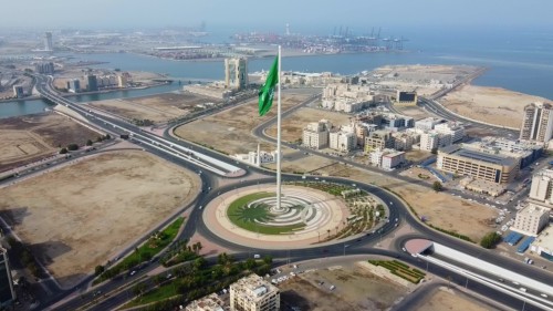 لقطات جوية لمدينة جدة بالمملكة العربية السعودية, تُظهر سارية العلم العالية التي ترفع علم السعودية بشكل بارز, مع خلفية البحر والمباني المحيطة.